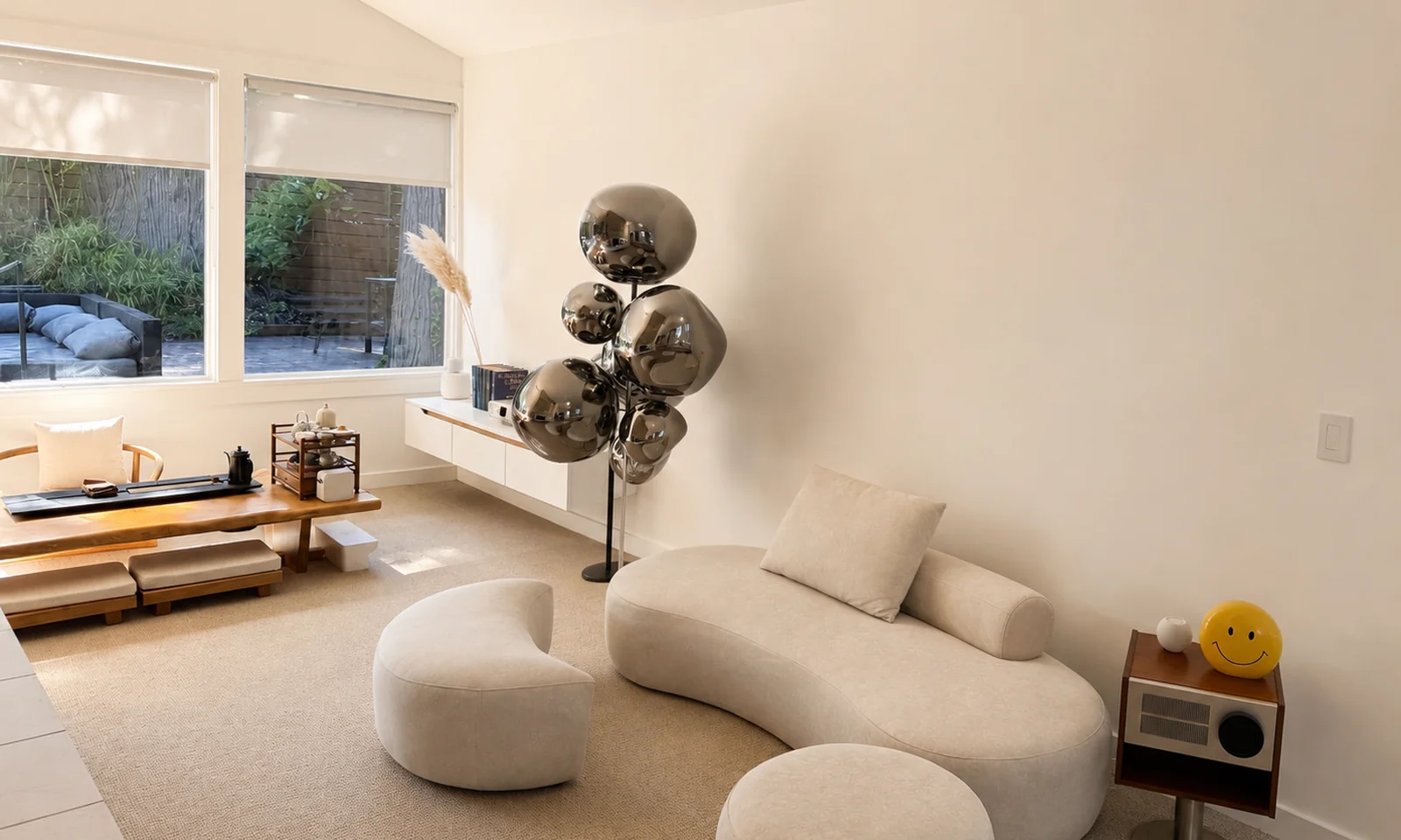 Living room of the suite with a curved sofa, footstools, and a low wooden tea table by the windows