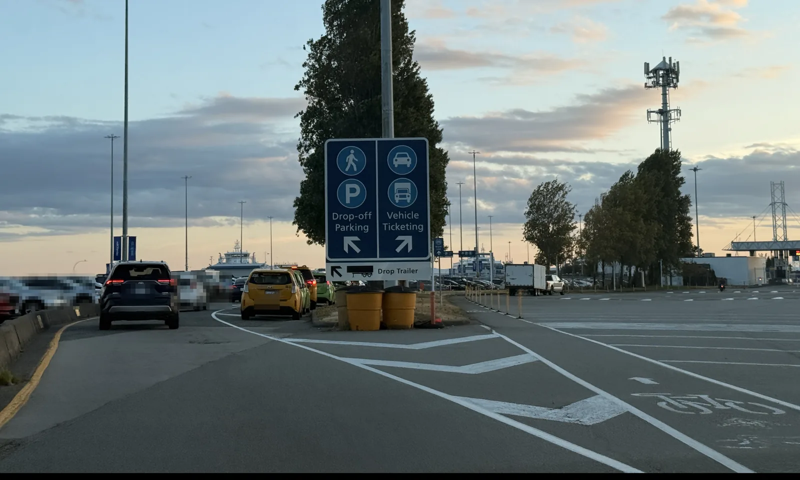 Sign at Tsawwassen Ferry Terminal pointing left to Drop-off Parking and right to Vehicle Ticketing, with taxis waiting in the drop-off lane